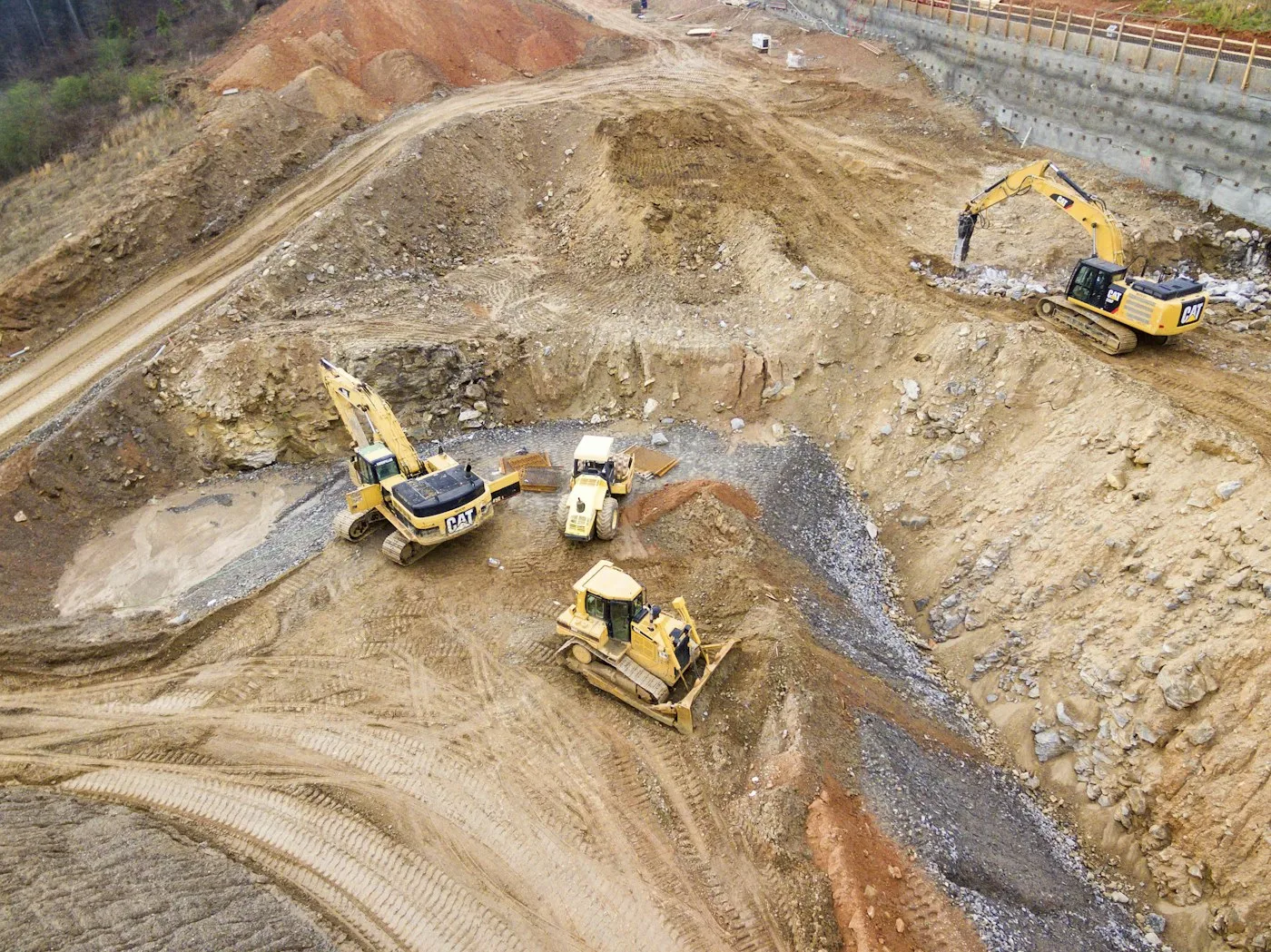 Excavators and a bulldozer working inside a deep building-site excavation